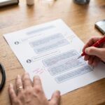 Mano de médico corrigiendo con bolígrafo rojo una conversación impresa con una inteligencia artificial